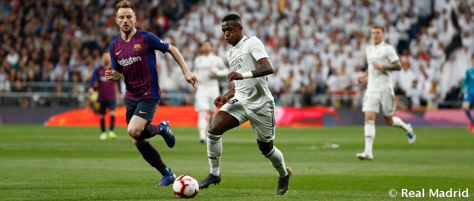 Vinicius conduce un balón ante Rakitic en un Real Madrid - Barcelona. Foto: Real Madrid Club de Fútbol.