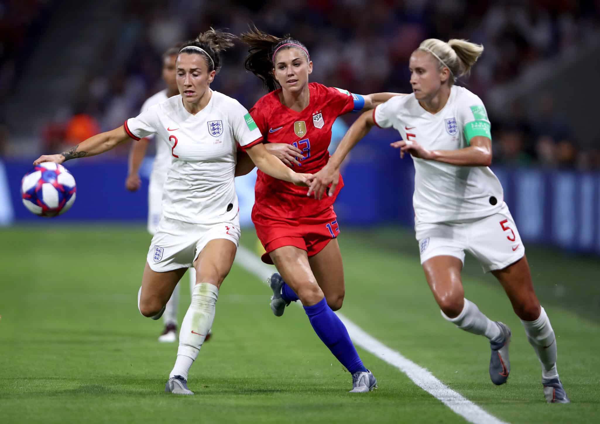 LYON, FRANCE - JULY 02: Alex Morgan of the USA is challenged by Lucy Bronze of England and Steph Houghton of England during the 2019 FIFA Women's World Cup France Semi Final match between England and USA at Stade de Lyon on July 02, 2019 in Lyon, France. (Photo by Alex Grimm/Getty Images)
