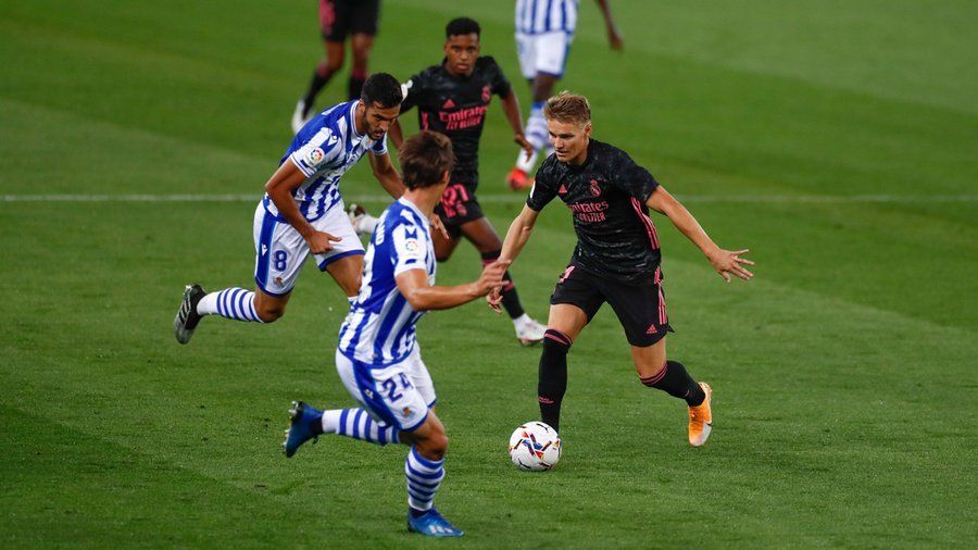 Martin Ödegaard conduce el balón ante Mikel Merino y Robin Le Normand en un Real Sociedad - Real Madrid Club de Fútbol. Foto: Real Madrid Club de Fútbol.