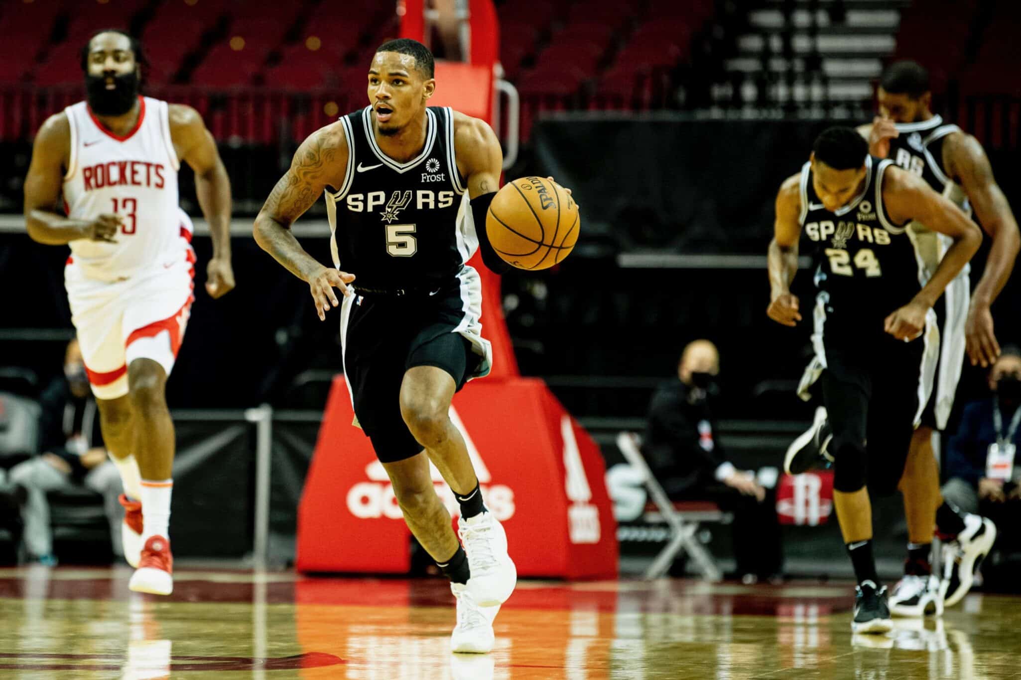 Dejounte Murray (5) avanza con la pelota con la presencia de James Harden (13) y su compañero Devin Vassell (24)