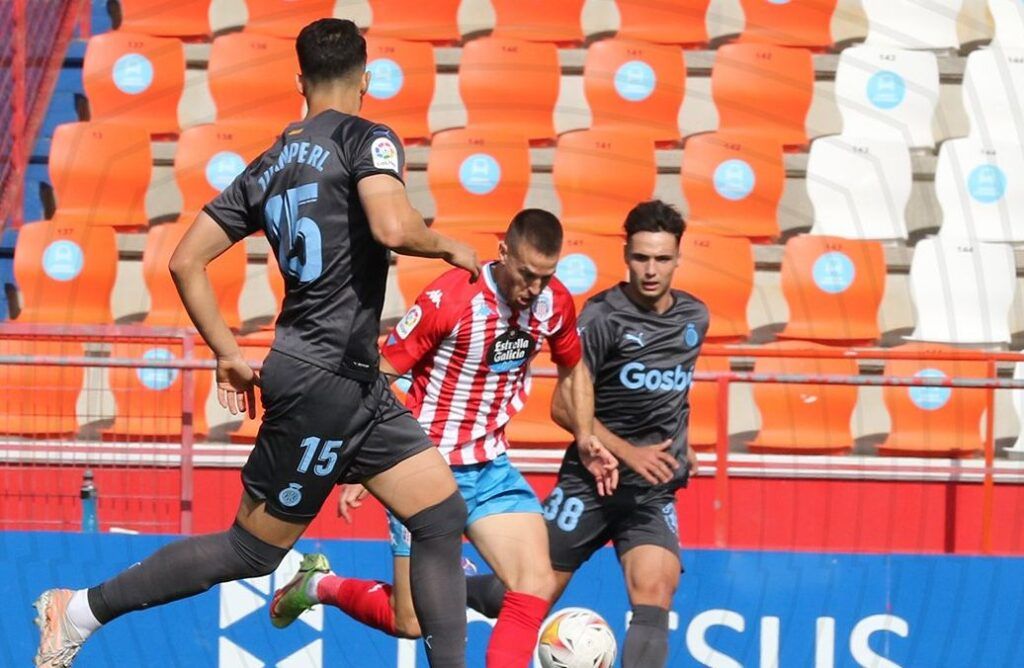 Chris Ramos intenta avanzar ante Arnau Martínez y la mirada de Juanpe en un Lugo-Girona