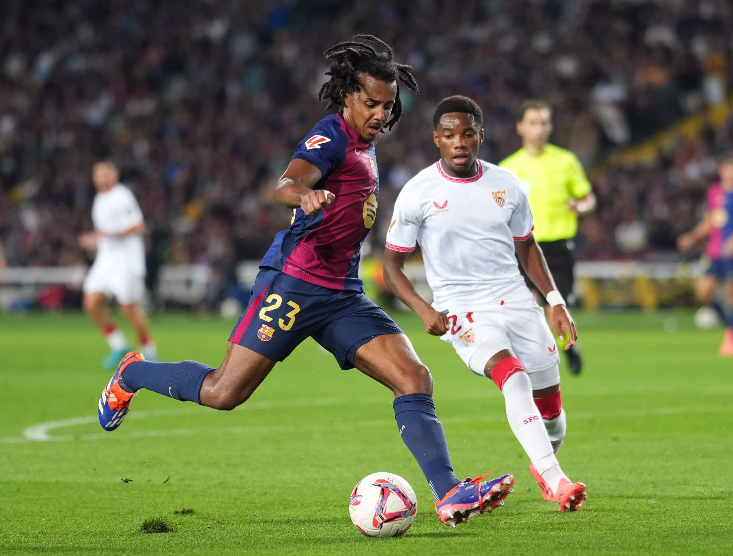 BARCELONA, SPAIN - OCTOBER 20: Jules Kounde of FC Barcelona takes a shot whilst under pressure from Stanis Idumbo Muzambo of Sevilla FC during the La Liga EA Sports match between FC Barcelona and Sevilla FC at Estadi Olimpic Lluis Companys on October 20, 2024 in Barcelona, Spain. (Photo by Alex Caparros/Getty Images)